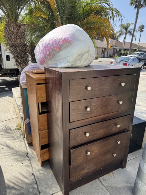 Dark wood dresser and a smaller chest staged at the curb for bulk furniture removal
