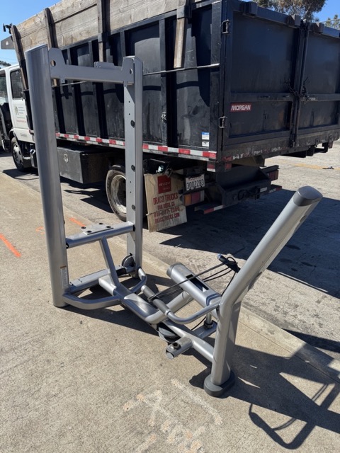 Heavy cable-machine frame beside a roll-off during a gym equipment haul