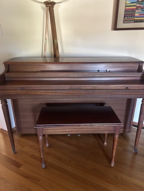 Upright piano and bench in a living room before indoor removal